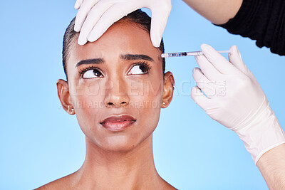 Buy stock photo Injection, hands and face of Indian woman for plastic surgery, cosmetics and skincare in studio. Dermatology needle, anxiety and surgeon and person for anti aging, derma and beauty on blue background