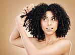 Afro, brush and hair of woman in studio for beauty, natural growth and grooming on brown background. Model comb curly hairstyle, coil texture and care for salon aesthetic, healthy treatment and shine