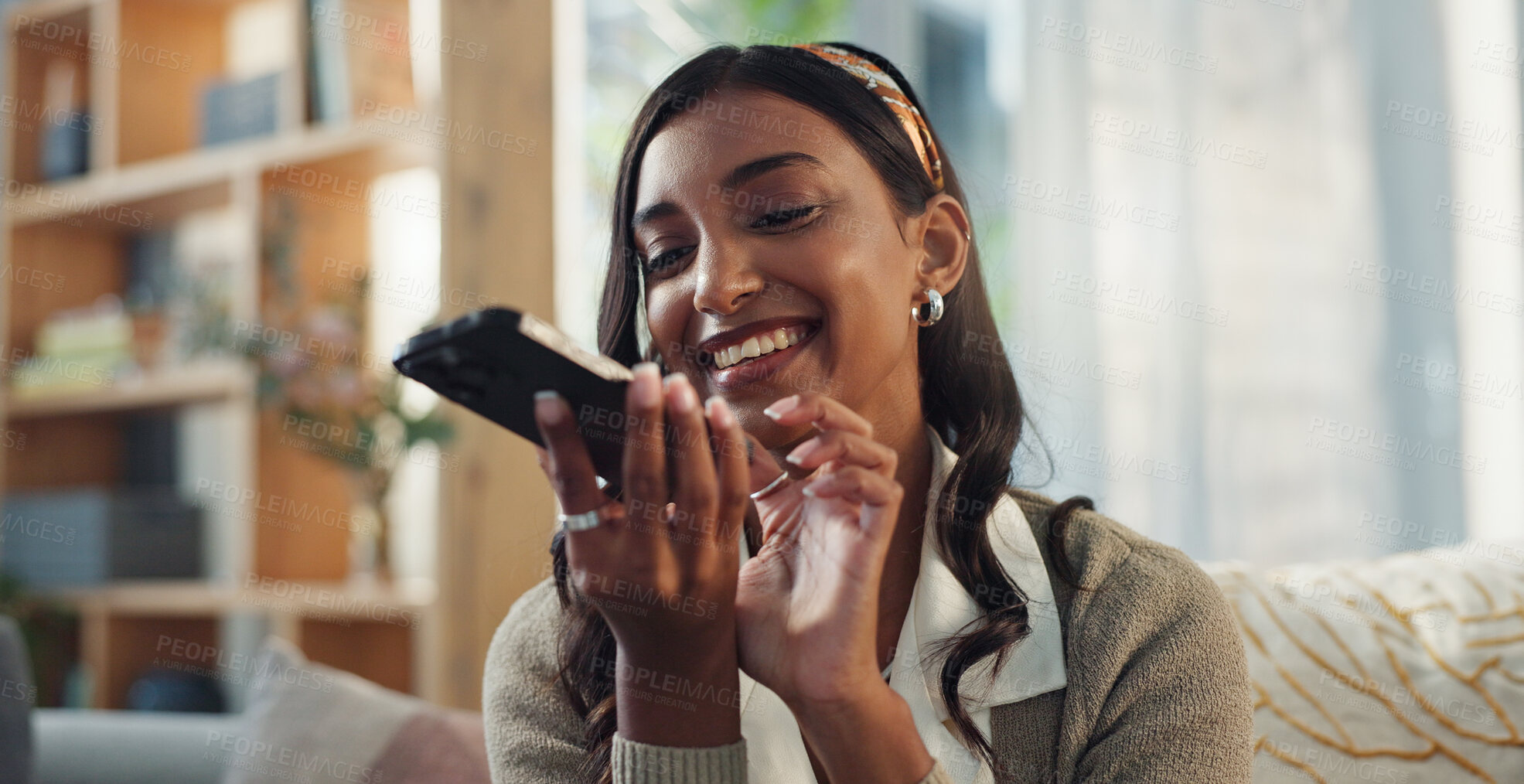 Buy stock photo Cellphone, talking and indian woman in home, smile and communication on speaker in lounge. Gossip, conversation and internet for networking online, female person and mobile discussion on phone call