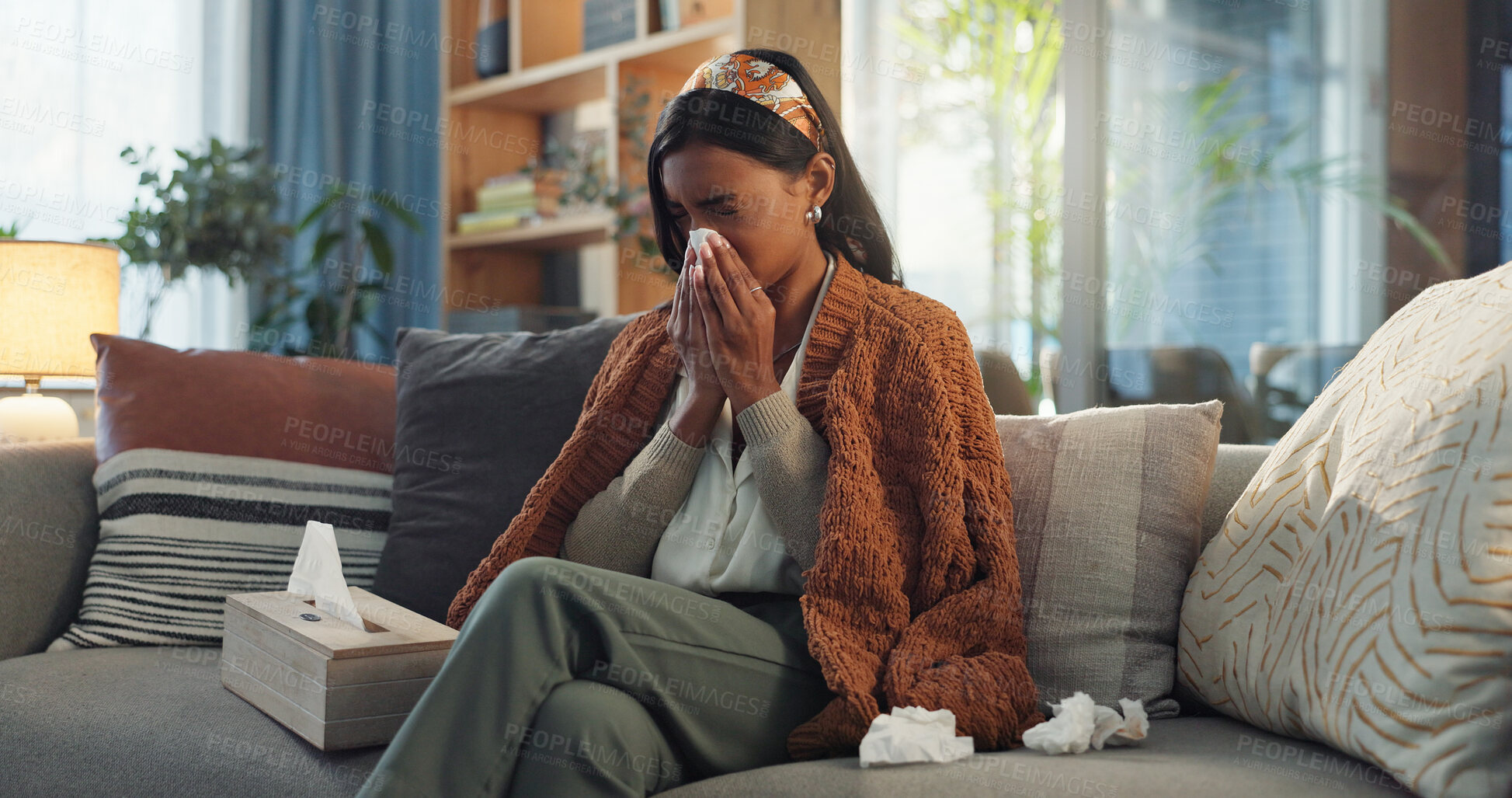 Buy stock photo Indian woman, house and sick with blowing nose on illness, flu and sinus in living room. Female person, sneeze and couch in lounge with blanket for fever, virus and allergy with tissue for infection