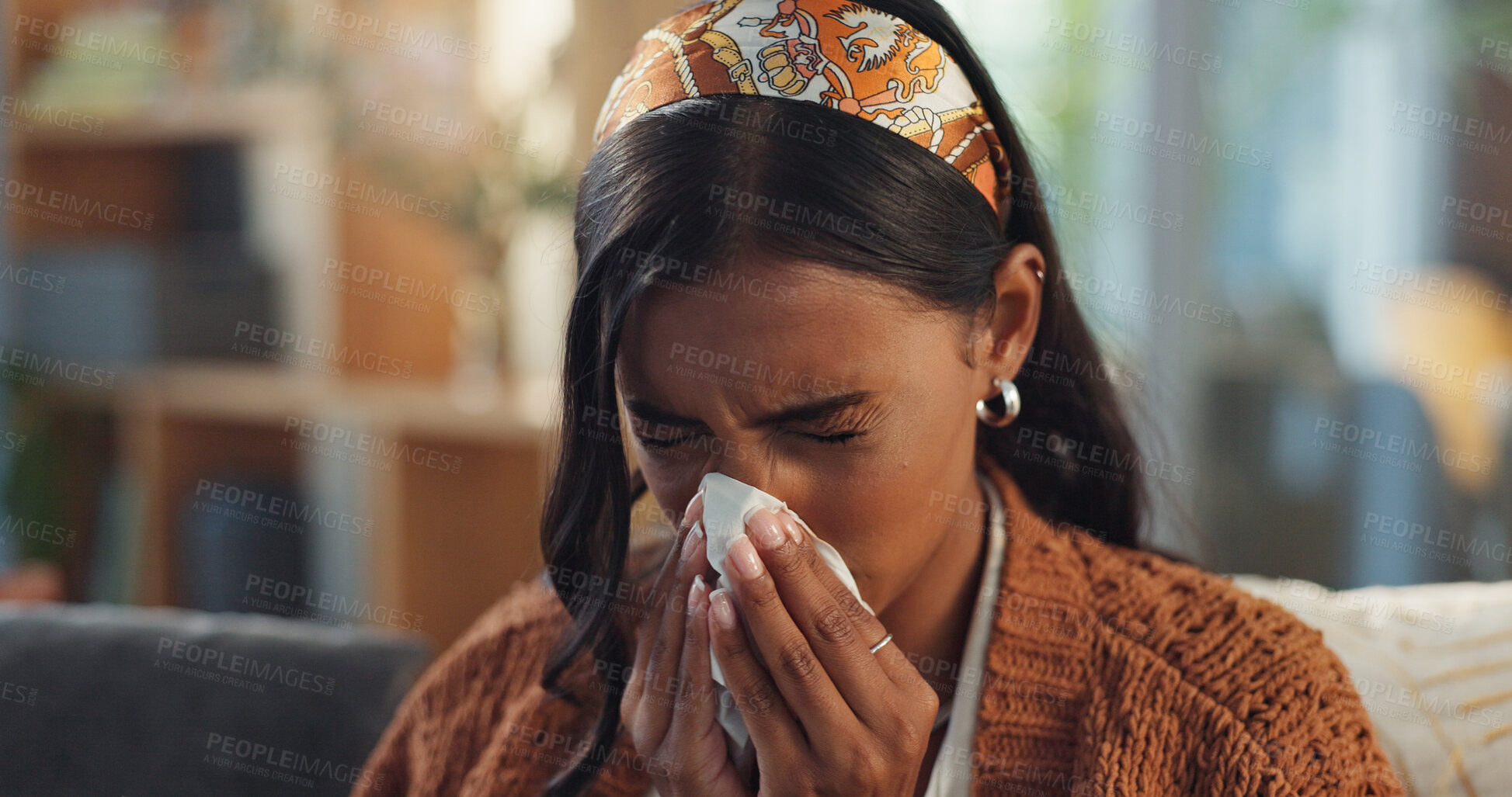 Buy stock photo Indian woman, home and sick with blowing nose on illness, flu and sinus in living room. Female person, sneeze and couch in lounge with blanket for fever, virus and allergy with tissue for infection