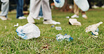 Cleaning, volunteer and people on grass with trash collection for sustainability, plastic and ngo project. Solidarity, garbage and hand with bag for charity, community care and social responsibility