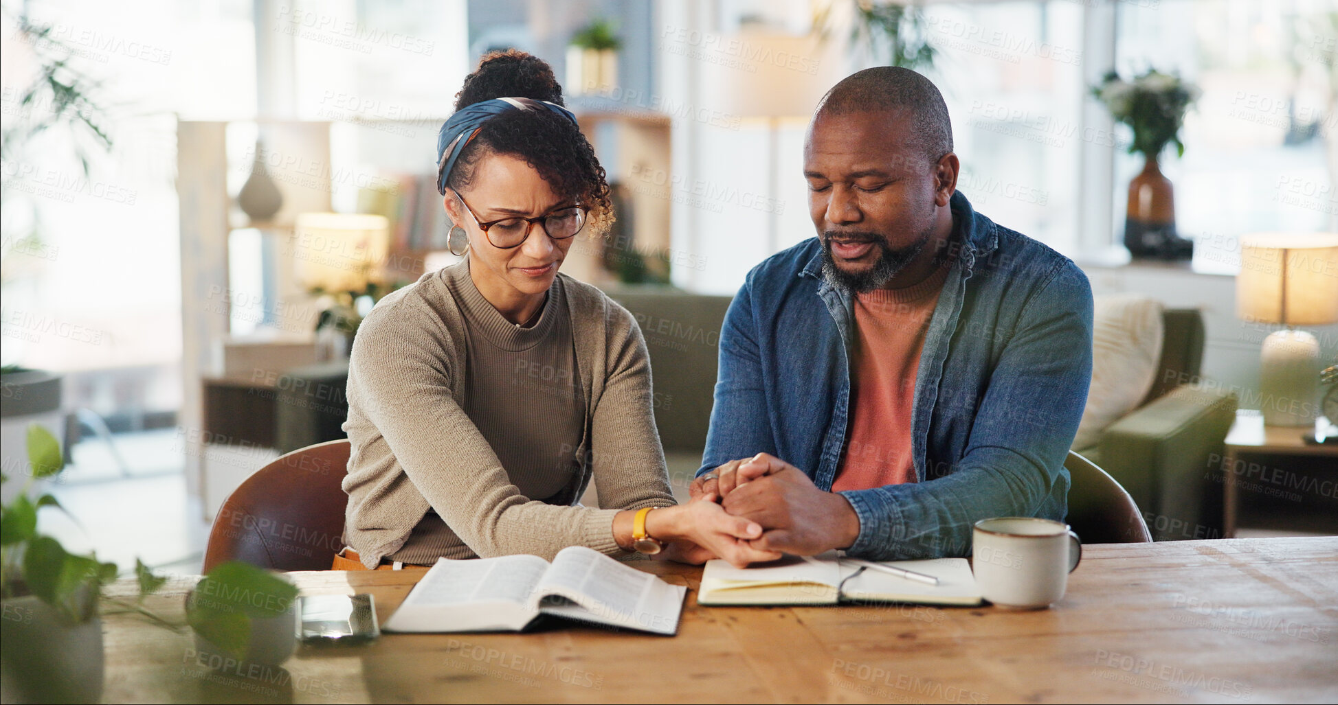 Buy stock photo Couple, holding hands and praying with bible for religion or spiritual guidance, belief and knowledge. Relationship, home and Christian with scripture on holy book for worship, gratitude and faith