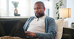 Laptop, relax and black man on sofa in home for research on holiday planning with flight ticket. Computer, living room and African male person reading online review for hotel booking with travel.