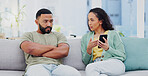 Phone, cheating and couple with argument on sofa in living room for divorce, affair or breakup. Cellphone, upset and young man and woman fighting for text with online infidelity on dating app in home