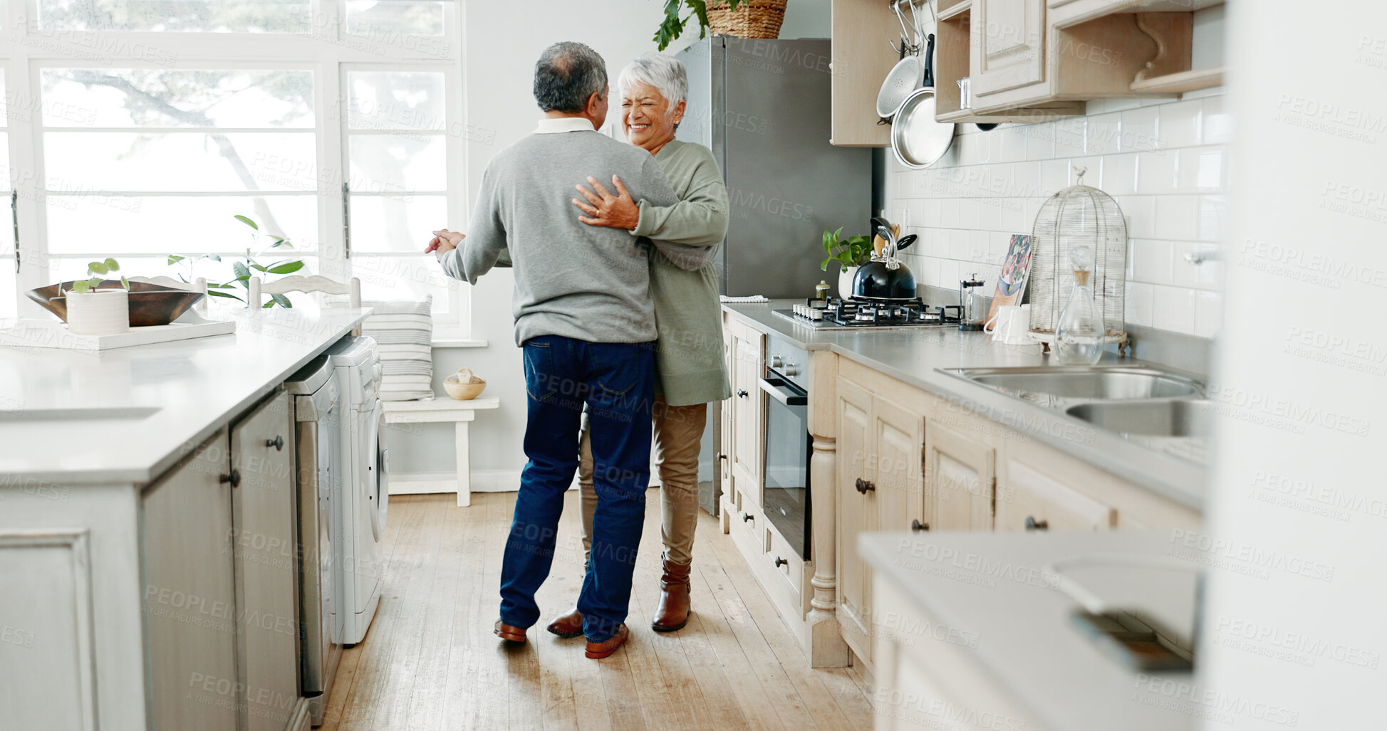 Buy stock photo Senior couple, dancing and love in home, support and funny conversation for laughing in kitchen. People, holding hands and together for connection in relationship, embrace and romance in marriage