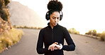 Watch, check and fitness of woman with headphones and exercise tech for progress tracking app on mountain road. Outdoor, training and African athlete with time performance monitor gear for workout