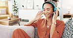 Happy woman, headphones and relax with music for listening, podcast or playlist on sofa at home. Young, female person or user enjoying audio streaming, sound or tune with headset or phone at house