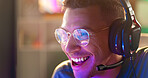 Happy man, face and gamer with headphones at night for esport, online tournament or streaming at home. Young, male person or streamer with smile or headset for fun console or computer gaming at house