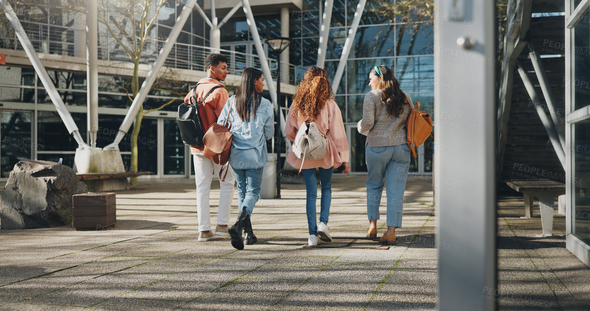 Buy stock photo Education campus, students and walking at college to class with talking, conversation or exam chat. Back, friends and diversity outdoor at university with backpack for learning, scholarship and study