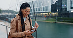 Woman, outdoor and happy with umbrella on smartphone in rainy weather on social media in Brazil. Female person, employee and smile or laughing online with texting, message and funny notification 