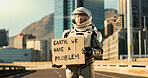 Person, astronaut and cardboard with helmet in city for dystopia awareness, message and alert of planet earth. Billboard, poster and travel news for future sustainability, protest sign and mission