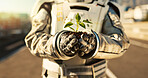 Hands, astronaut and outdoor with plant in city for scientific research, mission and experiment for environment. Spacesuit, closeup and portrait for growth, discovery and eco friendly project