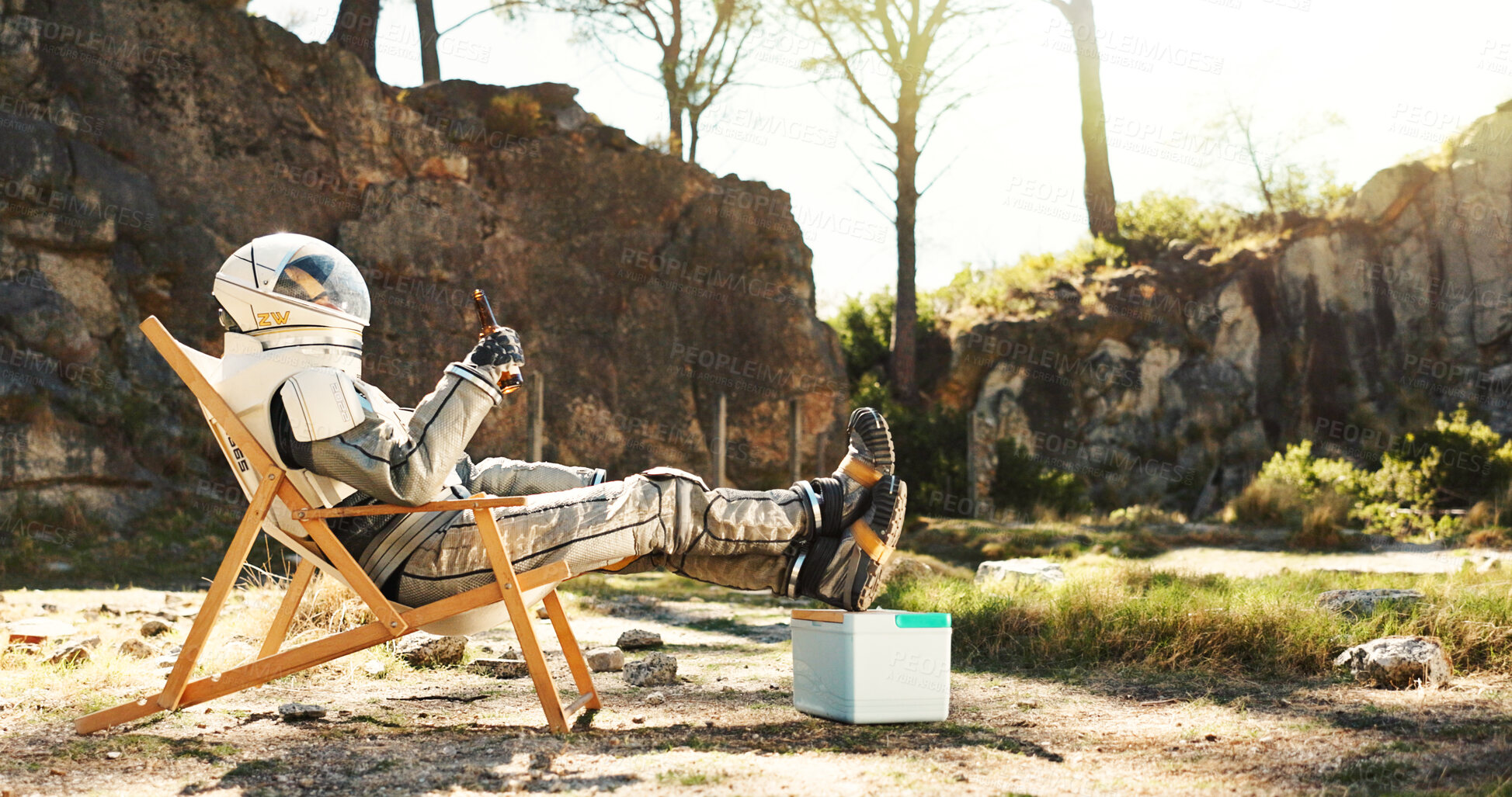 Buy stock photo Relax, nature and astronaut with beer on camping trip for vacation, holiday or getaway in Norway. Person, cooler box and space pilot with drink and resting outdoor in woods for weekend chill on break