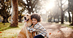 Trees, boy and dog in park, hug and bonding together with happiness, comfort and cheerful. Sunshine, outdoor and kid with pet lover, childhood and animal with embrace, carefree and weekend break