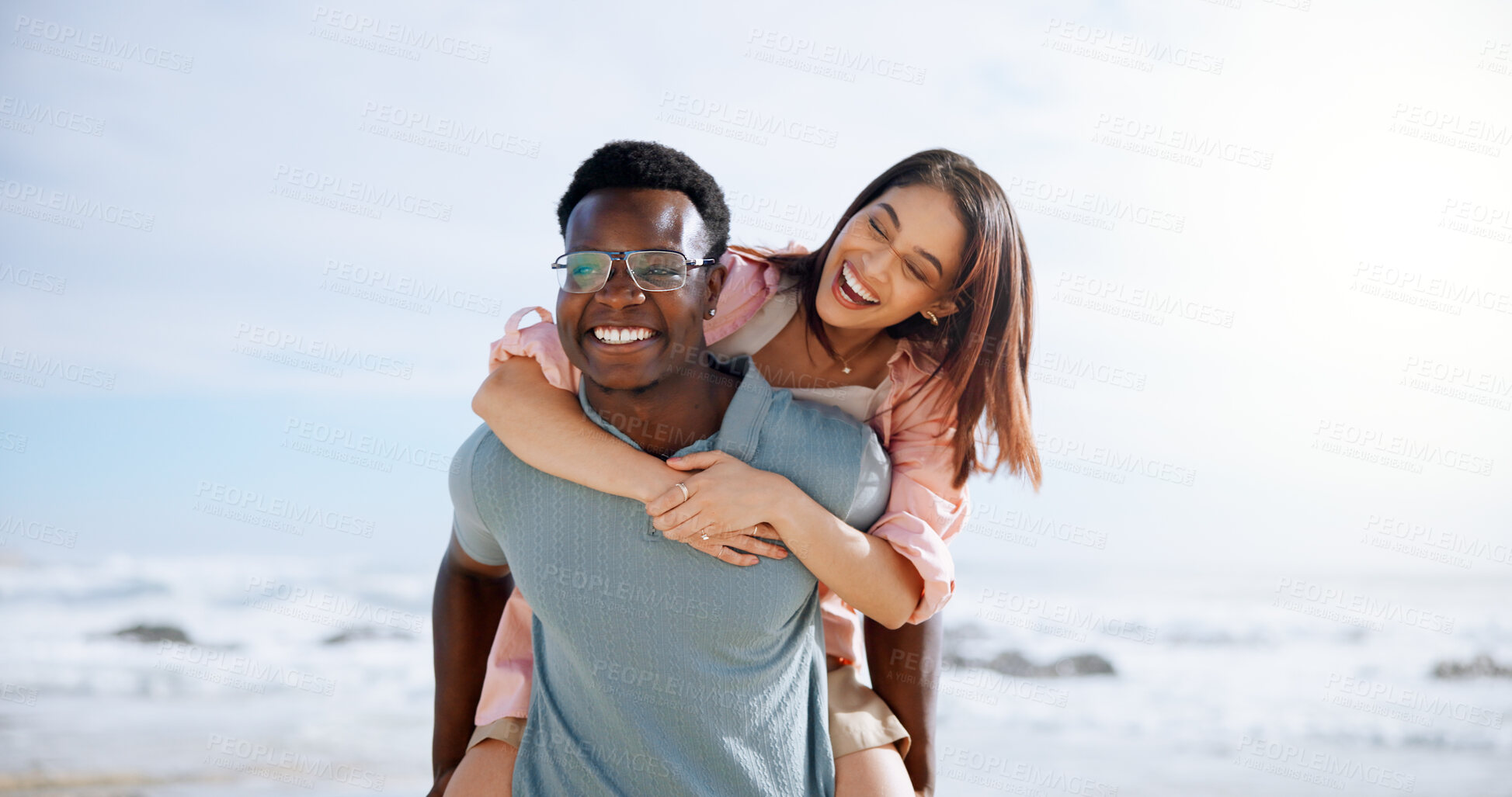 Buy stock photo Laugh, piggyback and happy with interracial couple at beach for travel destination, summer and honeymoon vacation. Relax, tropical and adventure with man and woman for holiday, bonding or romance