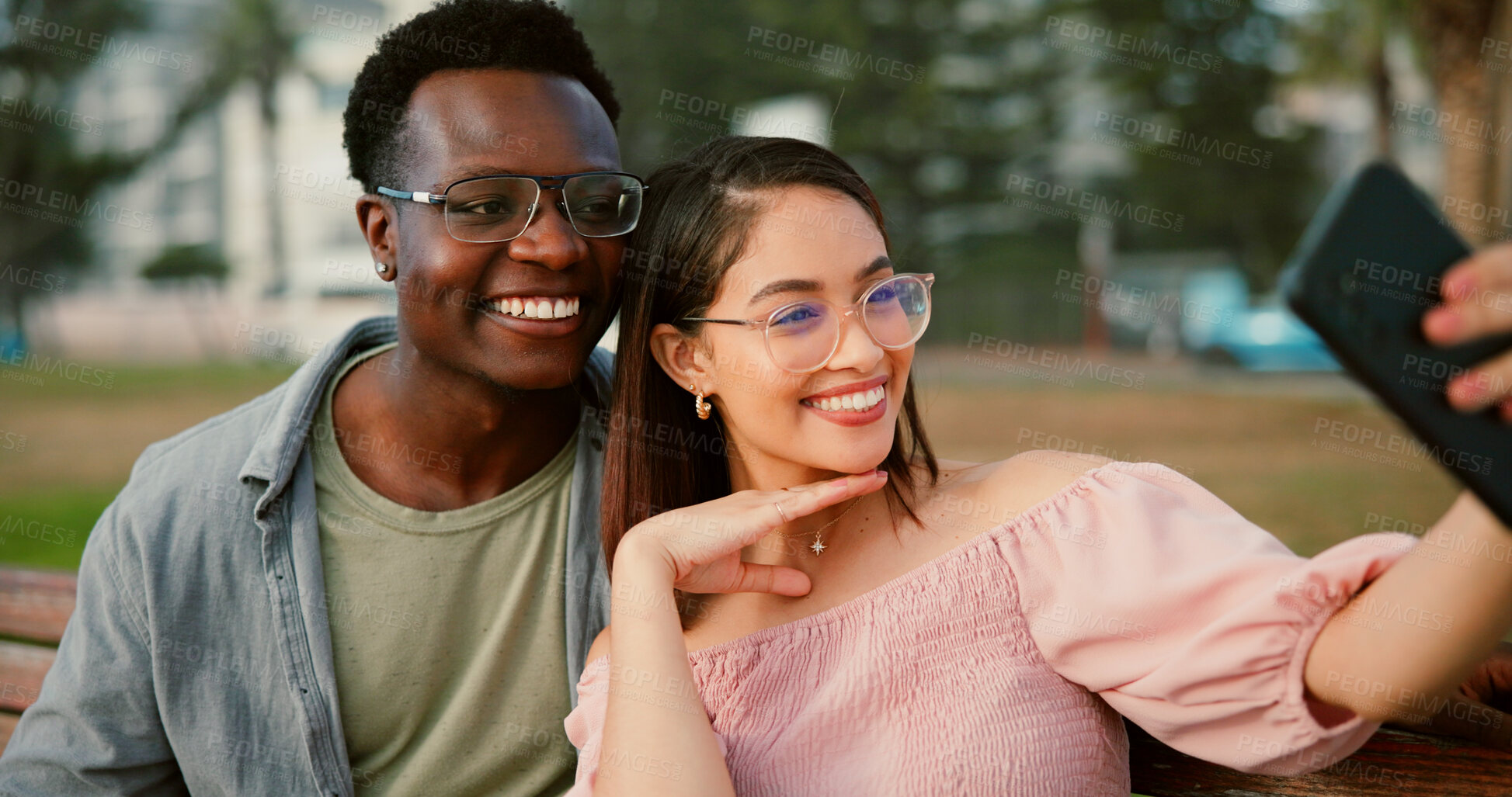 Buy stock photo Happy, selfie and couple on bench in park with fun memory, social media post and interracial relationship. Love, photography and man with woman smile on romantic date with outdoor bonding together