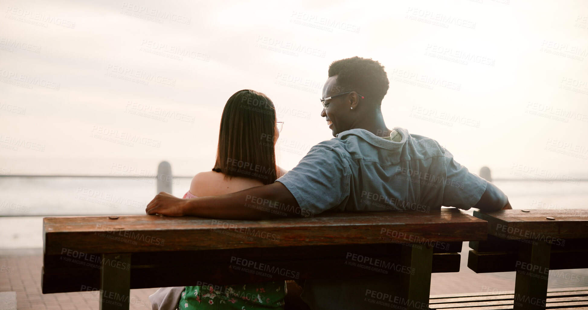 Buy stock photo Love, ocean and couple on bench for outdoor fun, bonding and care in relationship commitment. Romance, happy man and woman on date with laughing, relax and calm weekend holiday together from back