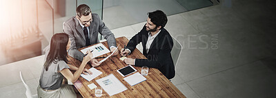 Buy stock photo Shot of three colleagues sitting around a meeting tablet in the office