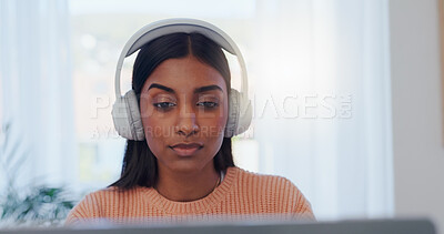 Laptop, music and reading with Indian woman in home office for online study or remote work. Computer, learning and listening with serious freelance employee in apartment for education or development