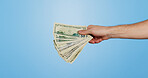 Money fan, dollars and hand of person in studio with offer, bonus or prize giveaway for financial loan. Cash, budget and model with bills for profit, savings or salary income on blue background space