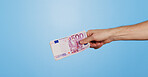 Money, euro and hand of person in studio with offer, bonus or prize giveaway for financial freedom. Cash, budget and model with bills for profit, savings or salary increase on blue background space