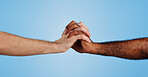 Care, unity and people holding hands in studio for change, collaboration and kindness in solidarity. Friends, love and gesture of support on blue background for human rights, trust or racial equality