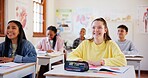 Happy children, students and teenagers with books in classroom for learning or education at school. Young, group or learners in diversity with smile, stationery or desk in class for youth development