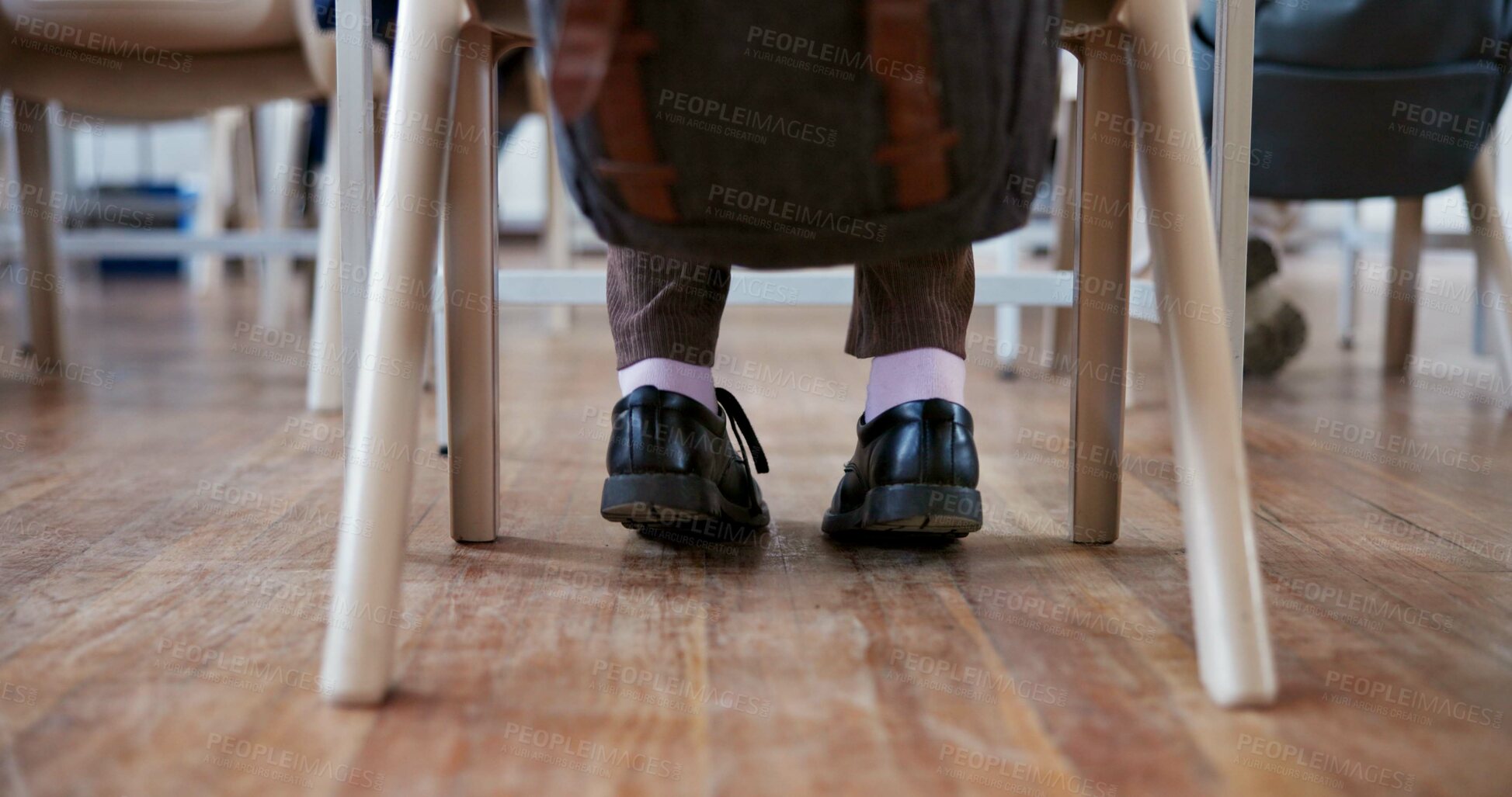 Buy stock photo Student, child and feet in classroom for learning with shoes, backpack and studying at desk for scholarship. Person, chair or legs at school with knowledge for development, academy or lesson on floor