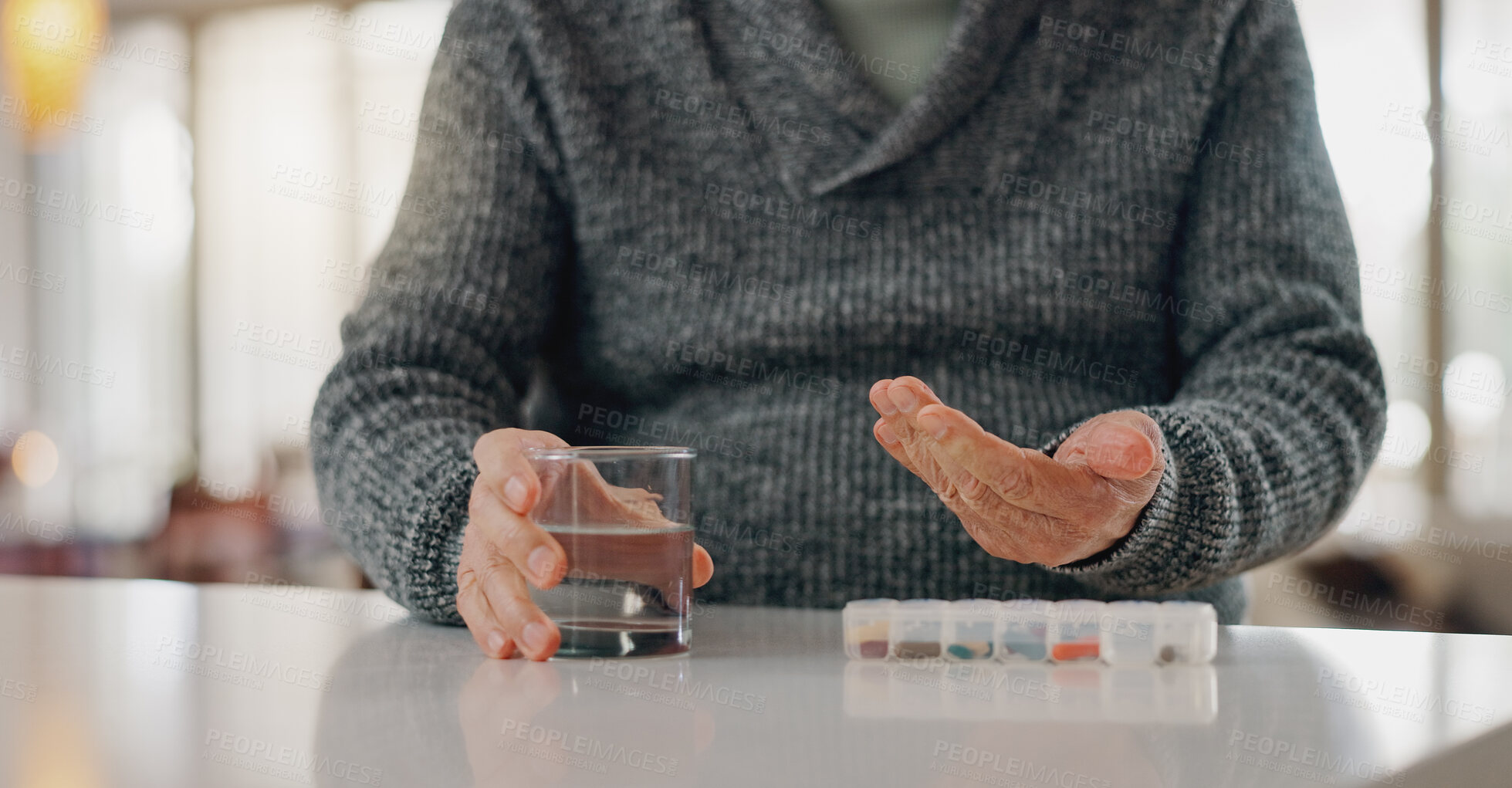 Buy stock photo Old man, hands and tablet container in home, arthritis treatment and water for antibiotics or drugs. Male person, healthcare and pharmaceutical organizer on table, pills and medication for joint pain