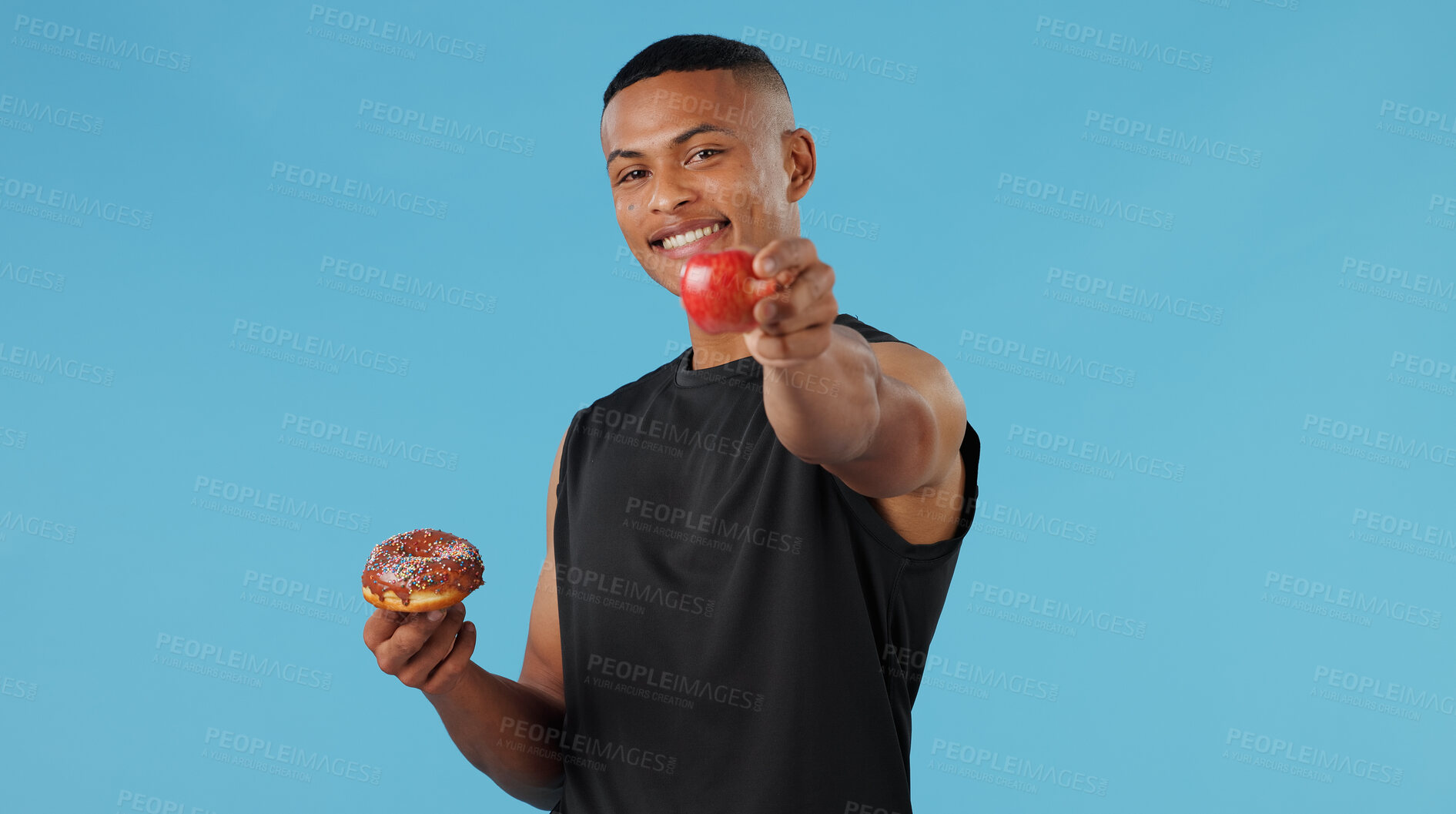 Buy stock photo Man, donut and apple in studio for health, nutrition and wellness with choice, vitamin C and versus. Male person, portrait and fruit on blue background for food, decision and weight loss with detox