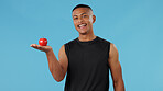 Man, portrait and apple in studio for health, nutrition and wellness with diet, vitamin C and fiber. Male person, healthy and fruit on blue background for food, eating and weight loss with detox