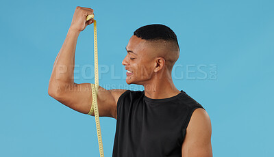 Buy stock photo Man, arm and measuring muscle in studio, check and bodybuilder flexing on blue background. Male person, fitness and strong guy for results of weightlifting, monitor progress and tool for development