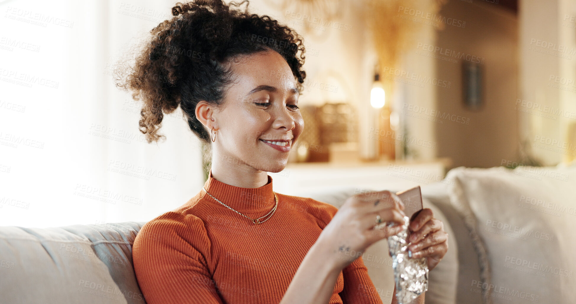 Buy stock photo Chocolate, relax and smile with woman on sofa in living room of home, eating candy for satisfaction. Eating, food and sugar with happy African person in apartment for snack or sweets on weekend