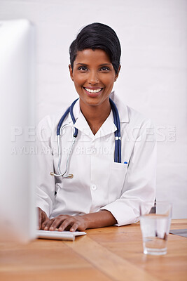 Buy stock photo Portrait, doctor and happy woman typing on computer in hospital for healthcare career in India. Face, smile and medical professional on keyboard for wellness and online research at desk in clinic