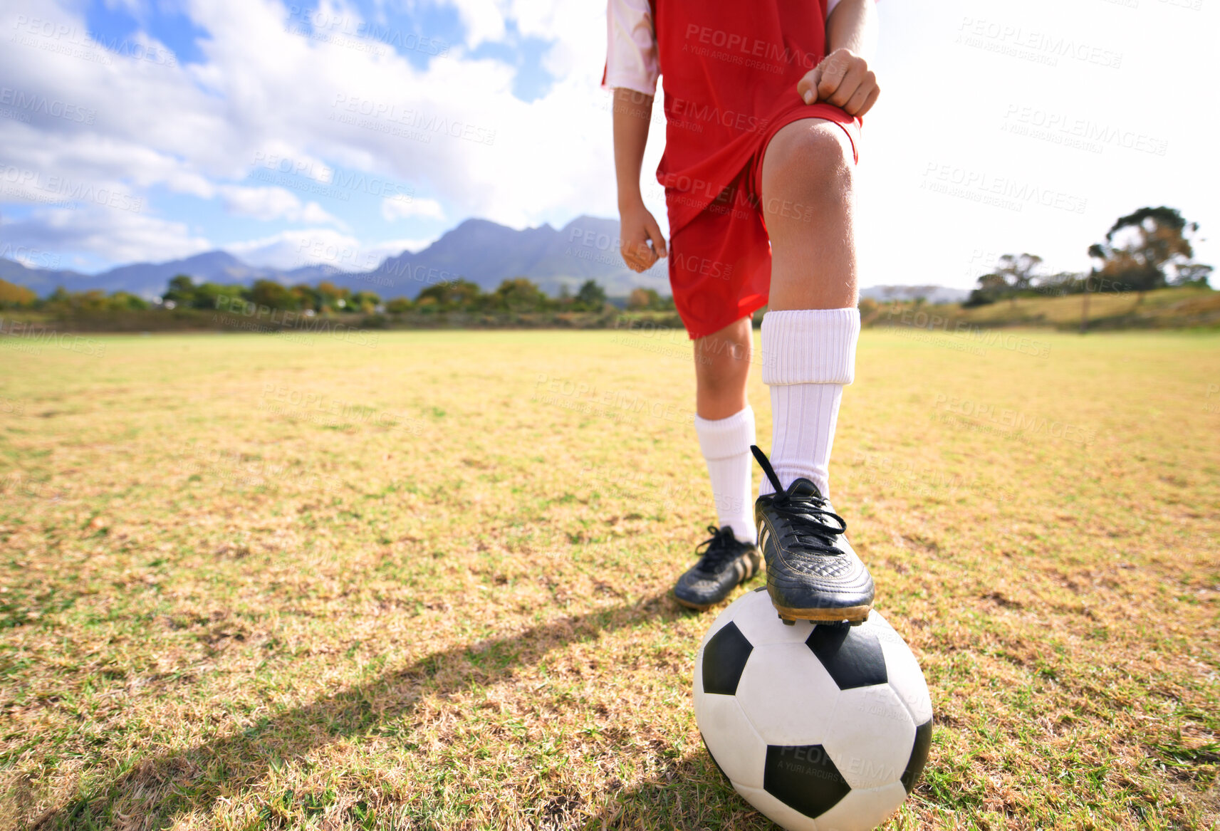 Buy stock photo Child, soccer ball and legs on green field for sports, training or practice with clouds and blue sky. Closeup of football player with foot ready for kick off, game or match on outdoor grass in nature