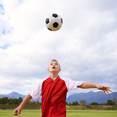 Buy stock photo Child, soccer ball and playing on green grass for sports, training or practice with clouds and blue sky. Young football player or athlete ready for kick off, game or match on outdoor field in nature