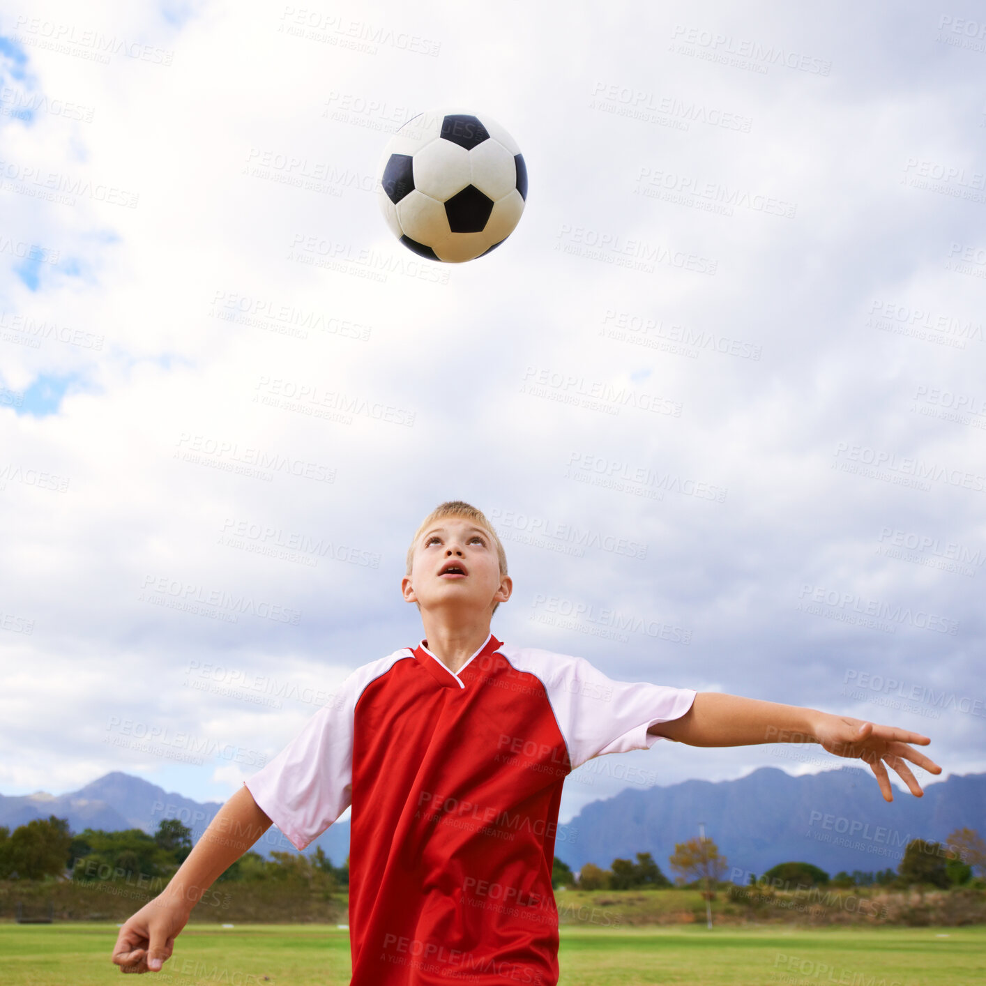 Buy stock photo Child, soccer ball and playing on green grass for sports, training or practice with clouds and blue sky. Young football player or athlete ready for kick off, game or match on outdoor field in nature