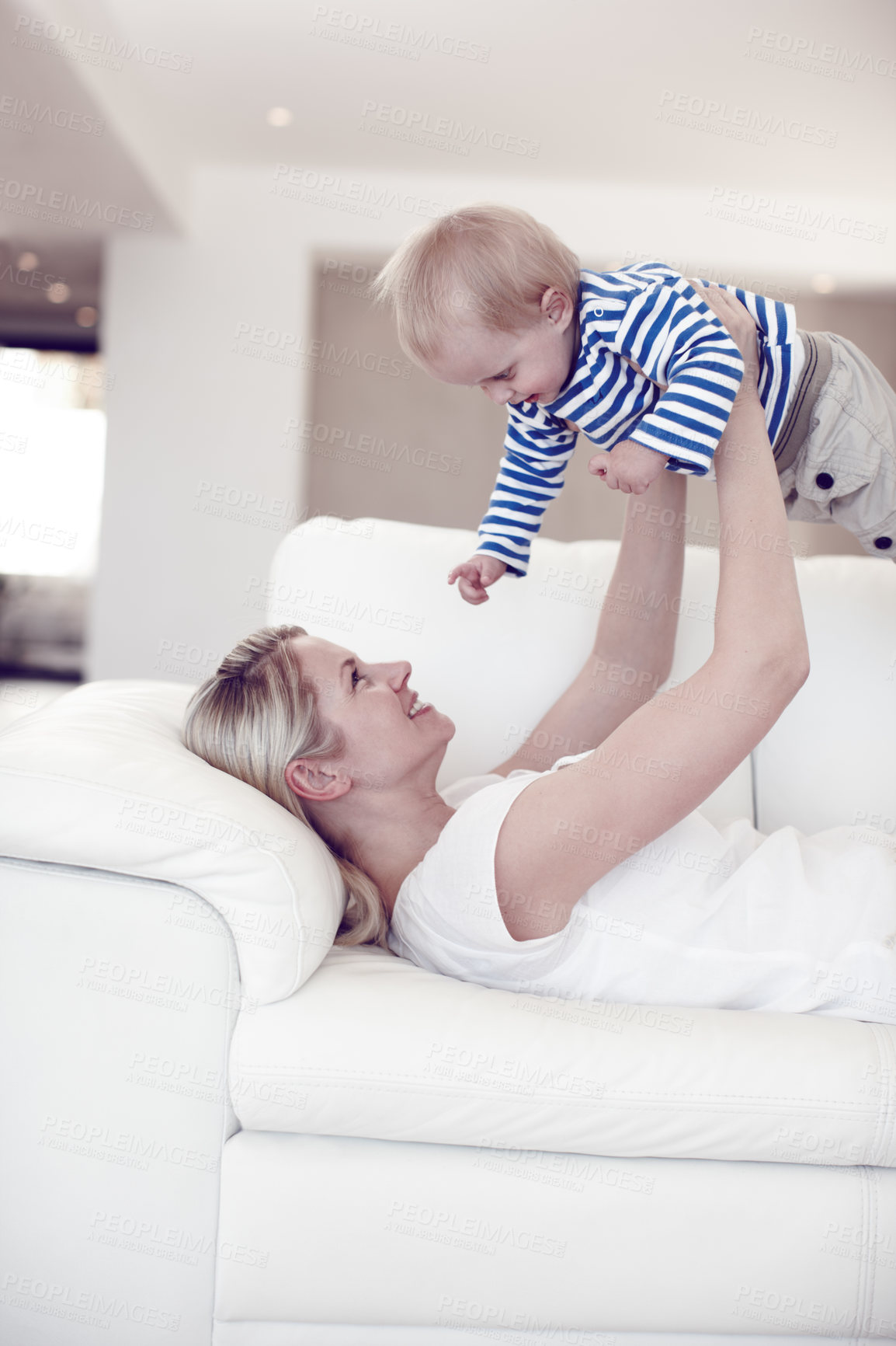 Buy stock photo Smile, mother and lifting baby on sofa for love, care and support in family home. Mom, kid and raise infant in living room for child development, bonding and playing game with happy parent to relax