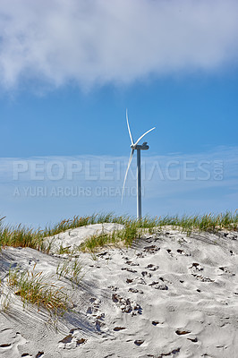 Buy stock photo Wind turbine, blue sky and beach with sand for renewable energy, alternative power or natural sustainability in nature. Empty, fan or eco friendly environment with resource, generator or green supply