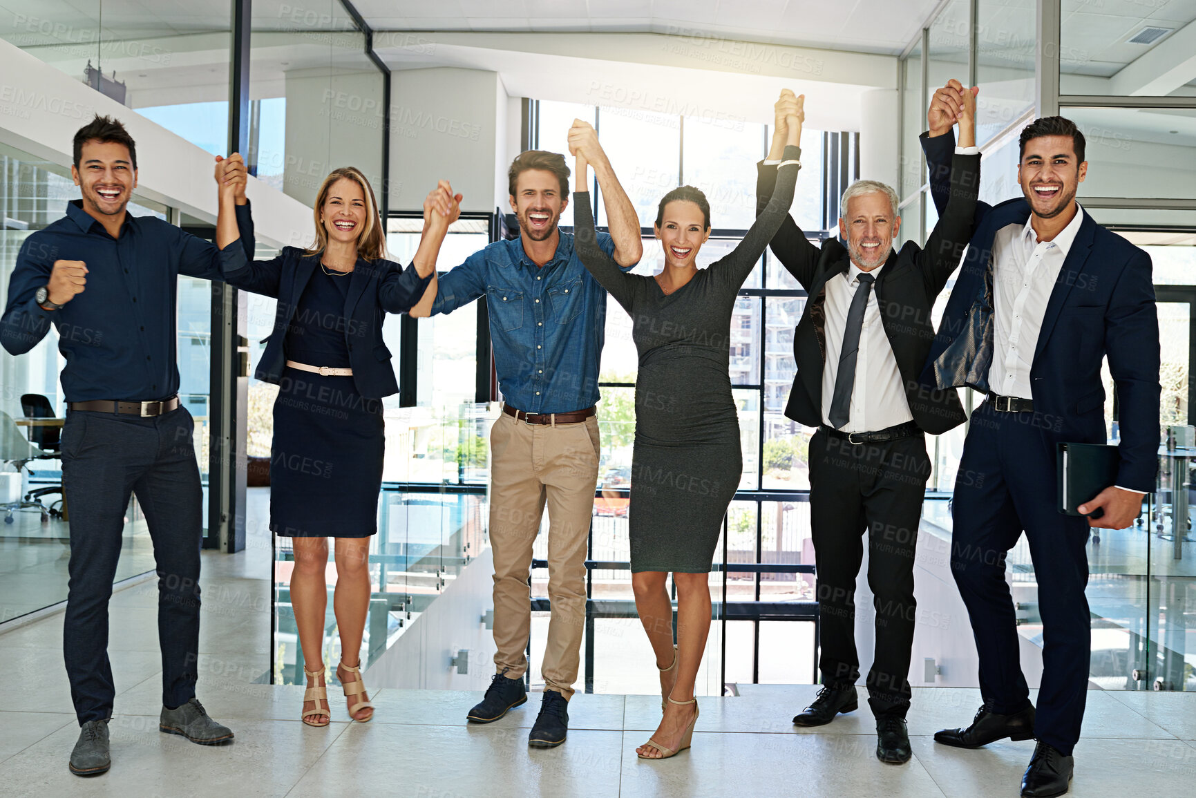 Buy stock photo Portrait of a confident looking team of coworkers sheering together while standing in a modern office