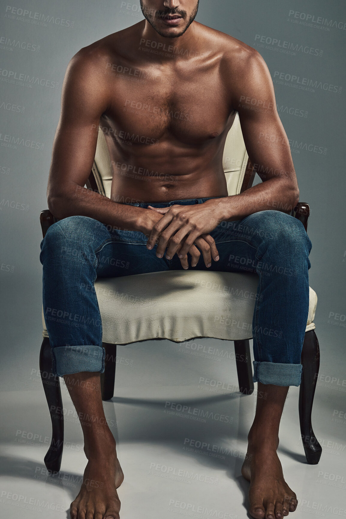 Buy stock photo Topless, health and fashion with body of man in studio for wellness, casual style and confidence. Jeans, designer and aesthetic with person on chair on gray background for muscle, art and cool