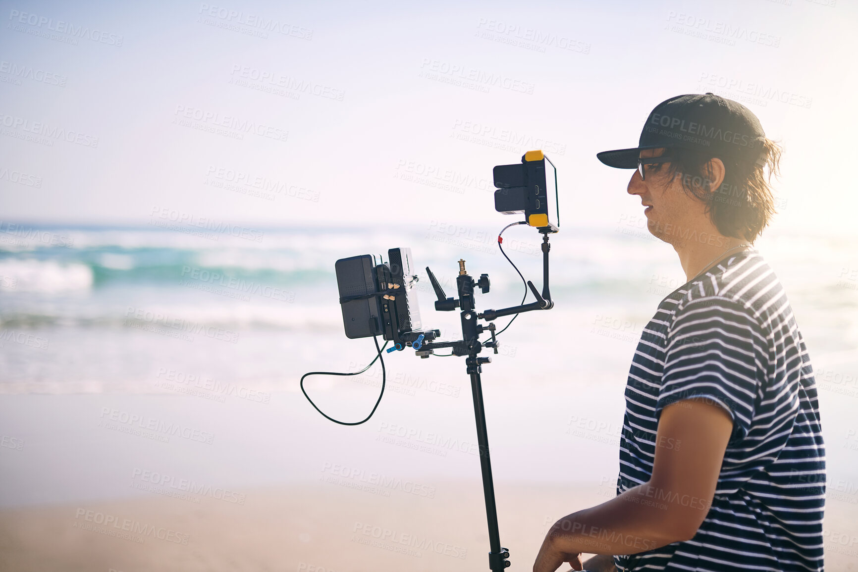 Buy stock photo Videographer, man and video camera at sea for film, photography production and nature documentary. Cameraman, recording and shooting with equipment outdoor for filmmaking at beach, holiday and travel