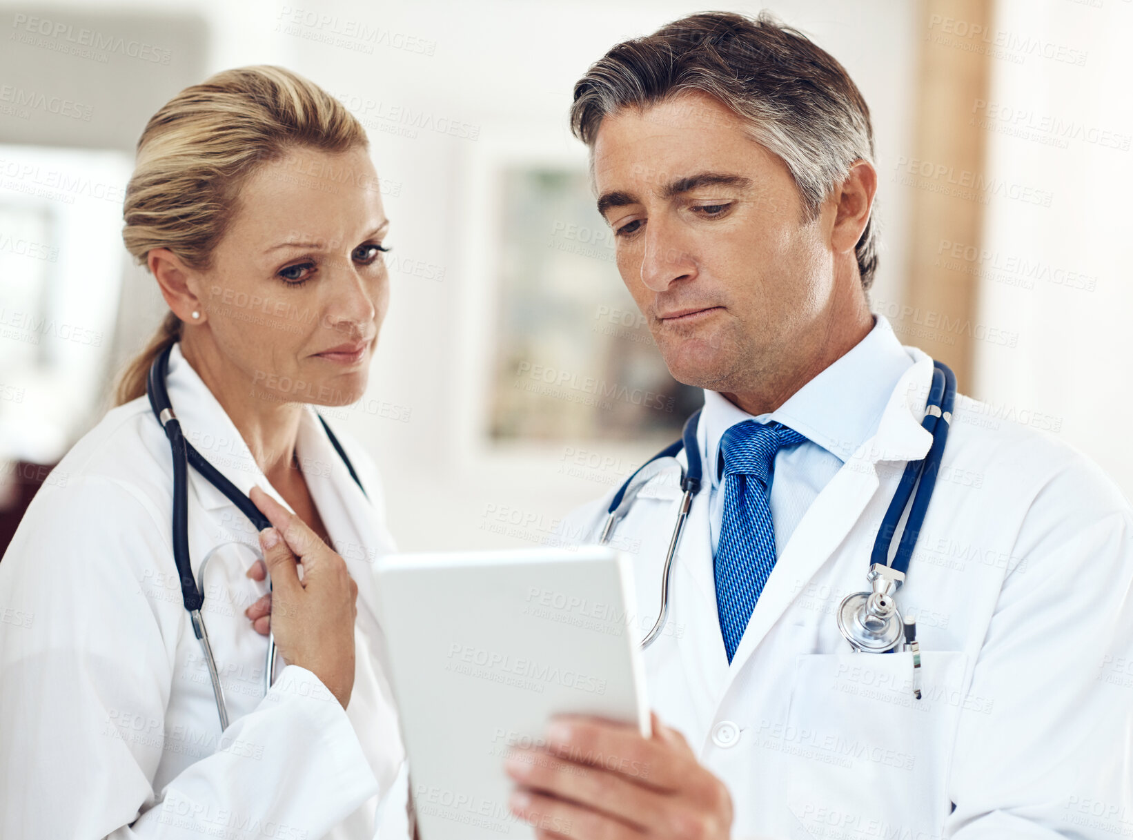 Buy stock photo Doctors, man and woman with tablet, reading and thinking for research, telehealth and app. Mature people, partnership and digital touchscreen for healthcare, report or review for wellness in clinic