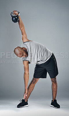 Buy stock photo Stretching, black man and kettle bell in studio for fitness, workout and exercise on gray background. Male person, serious and trainer with sportswear with training for health, wellbeing or self care