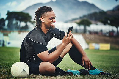 Buy stock photo Rugby, player and happy on field for mobile, communication and streaming online game with internet. African man, phone and social media on grass for sports app, video call and motivational podcast