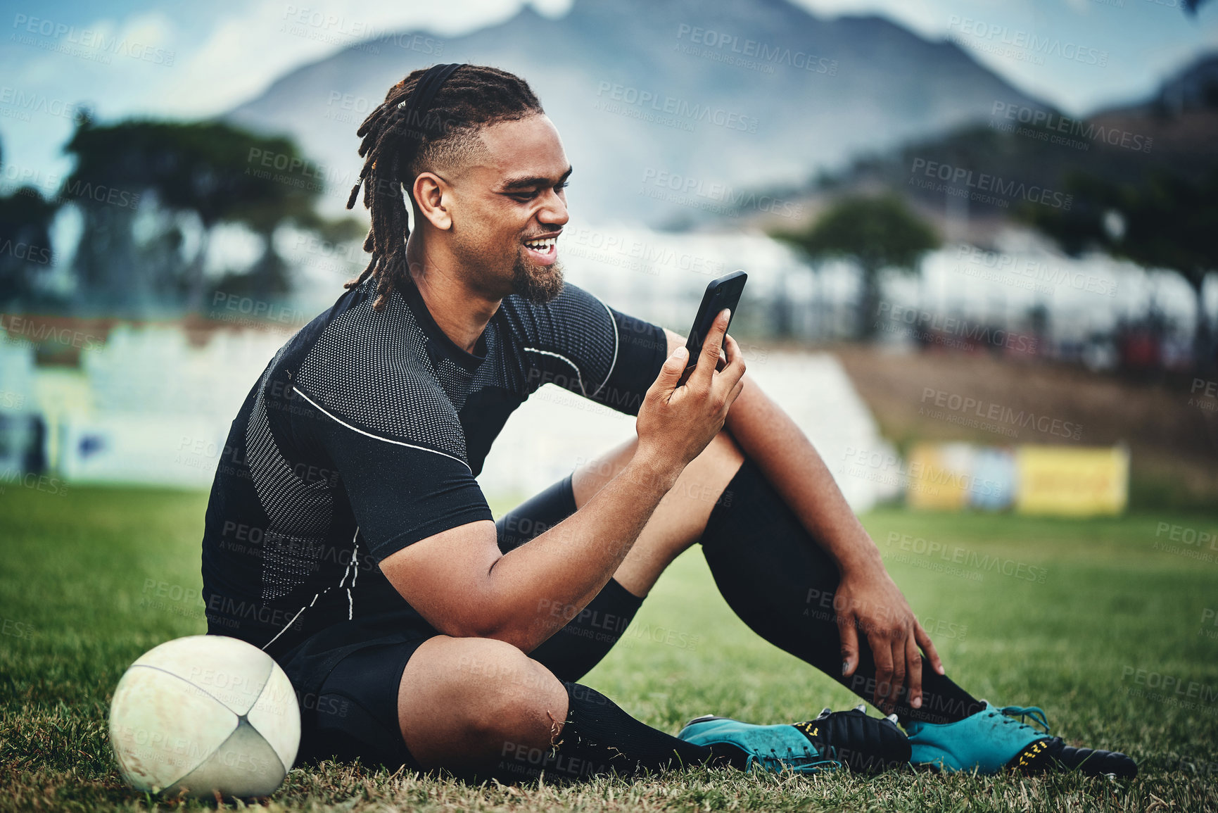 Buy stock photo Rugby, player and happy on field for mobile, communication and streaming online game with internet. African man, phone and social media on grass for sports app, video call and motivational podcast