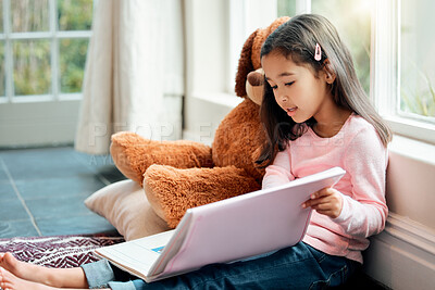 Buy stock photo Shot of a little girl reading a book at home