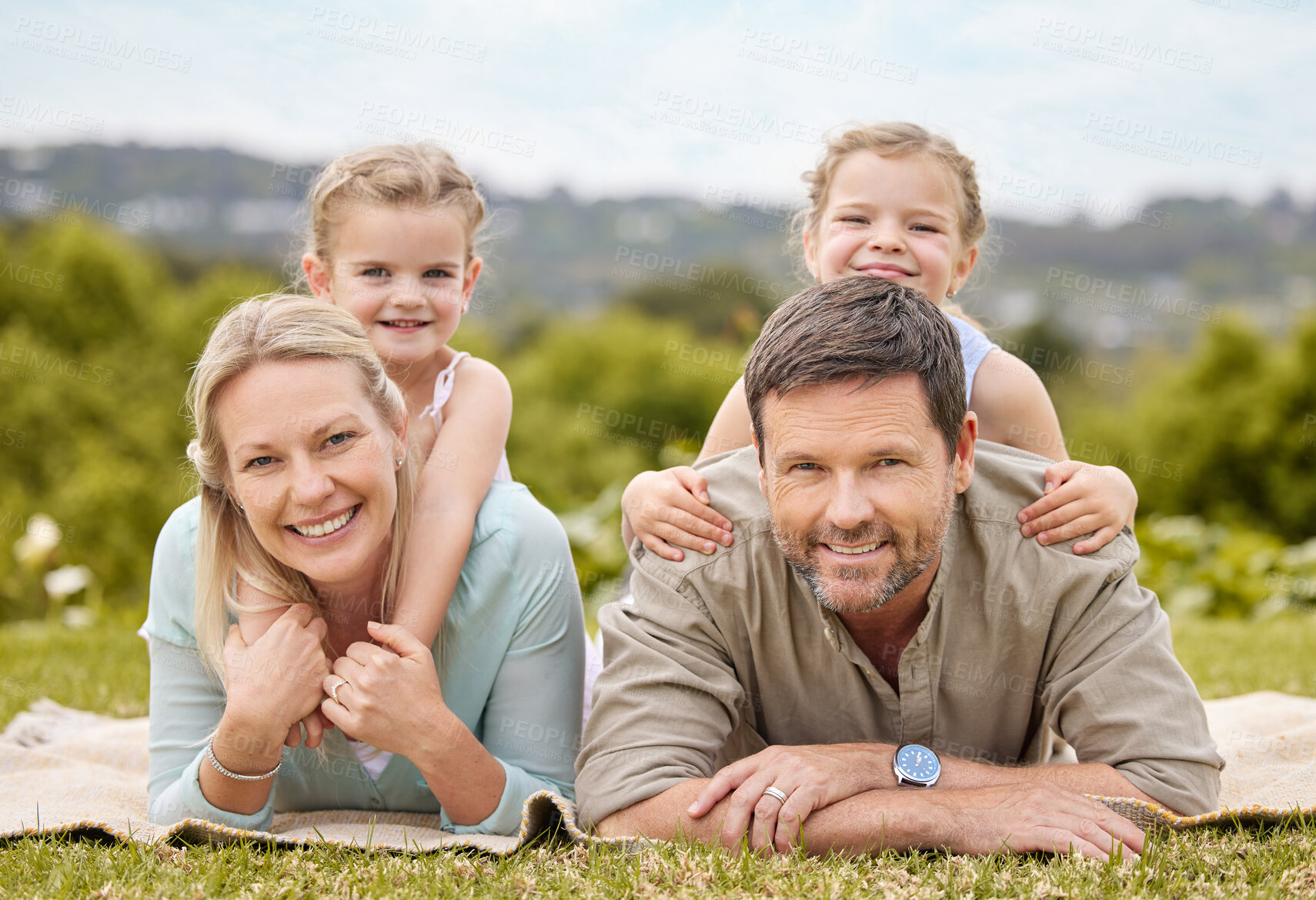 Buy stock photo Portrait, picnic and family in park with kids, smile and outdoor piggy back on weekend morning together. Mom, dad and girl children on blanket in garden for happy bonding, relax and love in nature