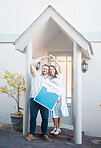 Young caucasian couple holding house keys while moving into new apartment. Happy man and woman holding for sale and sold sign outside home while relocating. Securing a loan for property or real estate